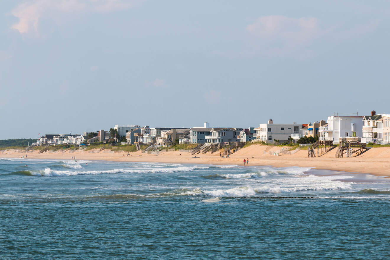 A coastal landscape with waves crashing on the shore in front of a line of beachfront houses in Virginia Beach